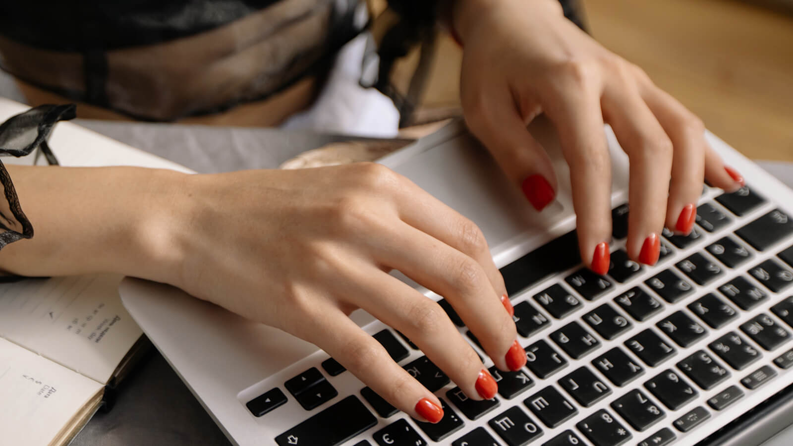 Woman's fingers typing on a laptop keyboard.