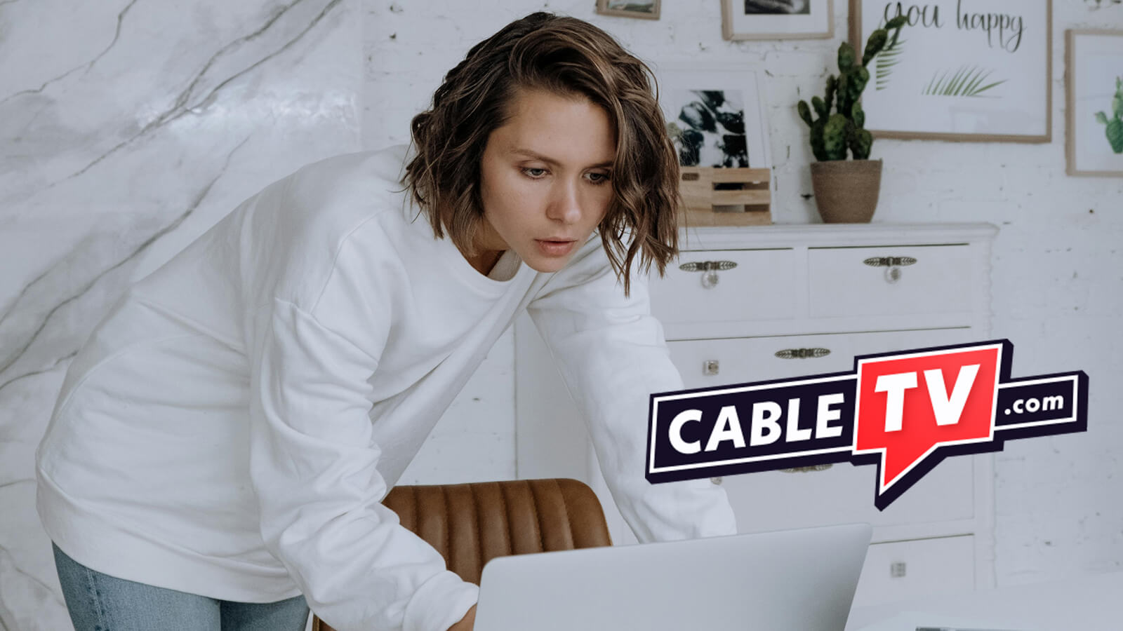 A woman looking at a laptop computer screen, with the CableTV.com logo overlaid on the image.