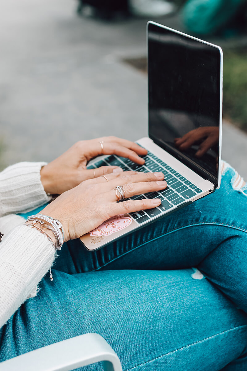 A woman's hands typing on a laptop.