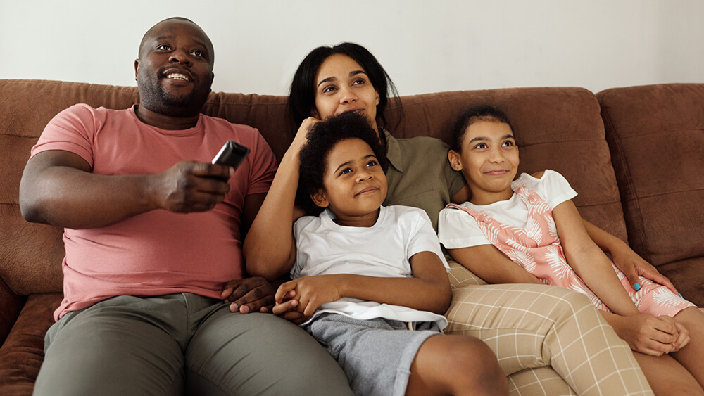 A family on a couch watching TV together.