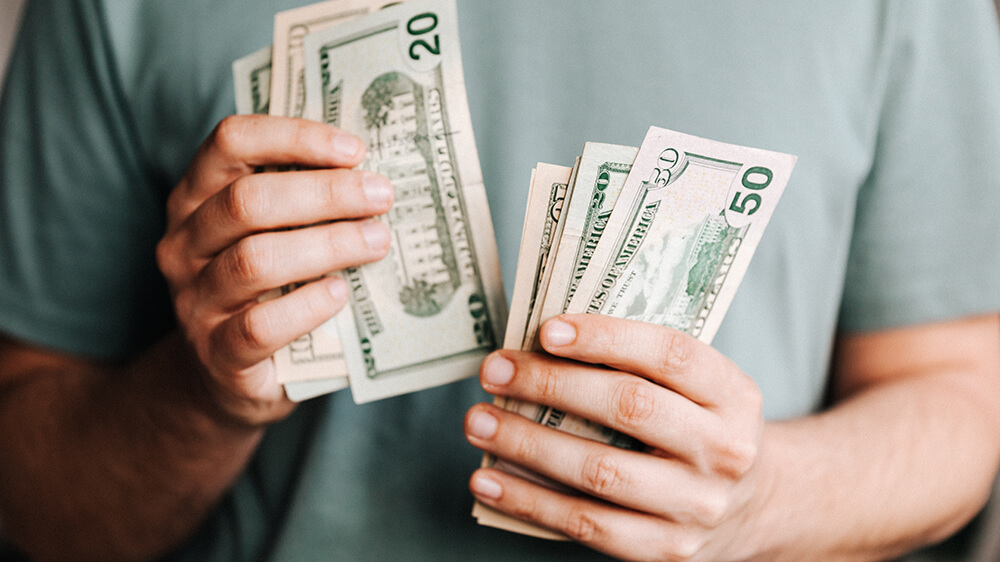 Close up of a person holding twenty and fifty dollar bills.