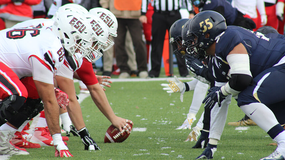 Two football teams lined up on the field getting ready to snap the ball.